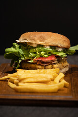 Delicious vegan burger containing chives, mushrooms, tomato, arugula, basil pesto and vegan mayonnaise with French fries