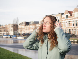 Relaxed Young Woman Enjoying Music by the Riverside