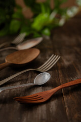 Close up of vintage rustic tea spoon with group of forks and spoon out of focus over dark wooden table 