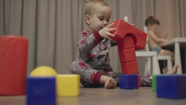 Toddler little boy playing toy blocks and builds towers. Educational play toddler learning and educate with game constructor hand-eye coordination delighting in process of building toddler playing