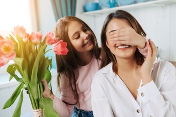 happy mother's day! child daughter congratulates mother and gives a bouquet of flowers to tulips.