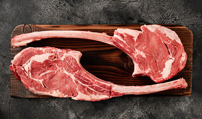 Raw tomahawk steak on wooden board