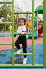 Obraz premium Baby girl having fun climbing stairs in playground.