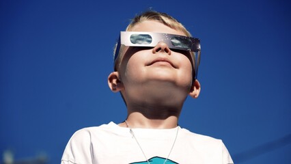 A young boy safely looks at a total eclipse while wearing protective glasses. 