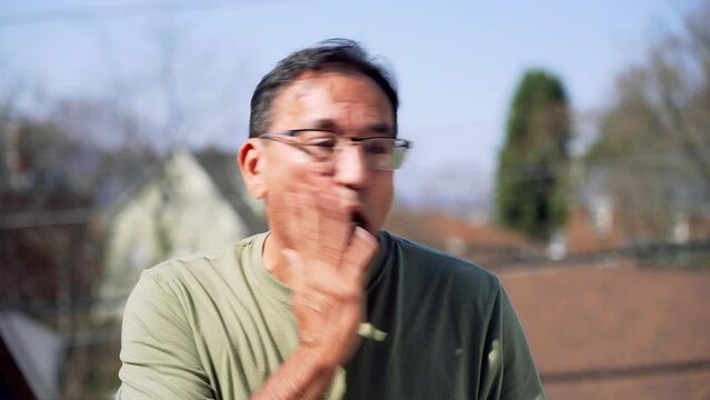 A slow motion view of a surprised man slapping himself in the face.  	