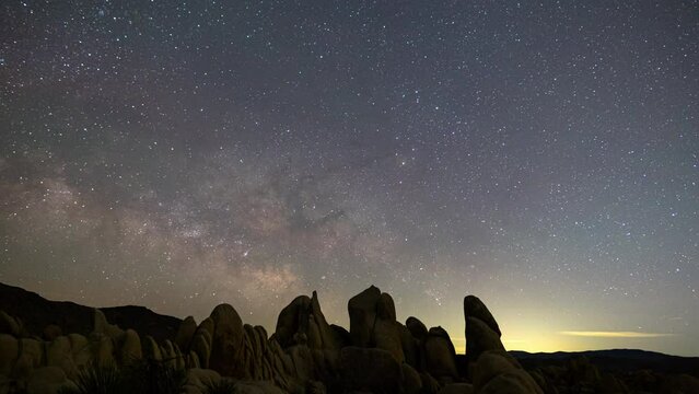 Timelapse of Milky Way galaxy rising over rugged boulders in Joshua Tree National Park, California 