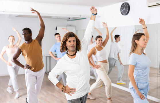 Group of happy young adult multinational sports people exercising dancing in modern gym studio