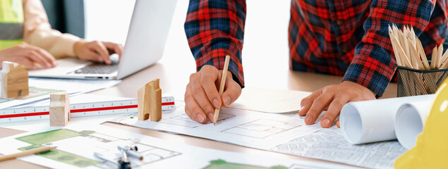 A cropped portrait of professional architect working with blueprint during safety engineer using...