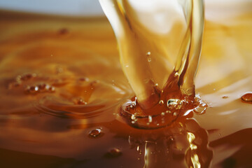 Macro shot of golden liquid splash made up of melting gummy bear in hot water