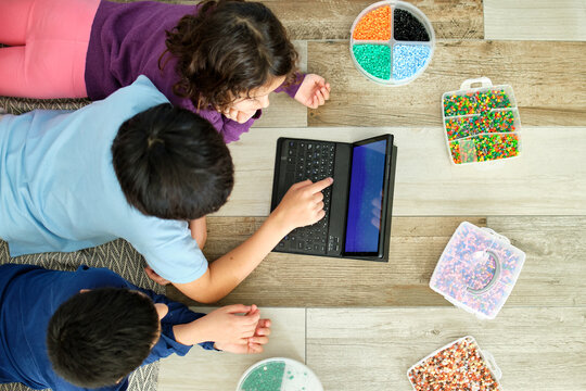 Children engaging in creative play with beads and laptop