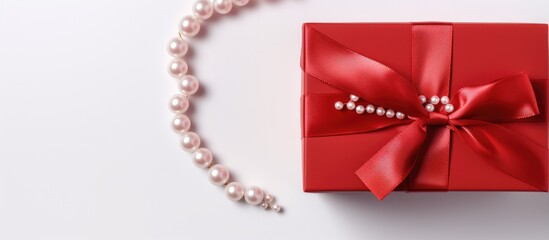 Red gift box with pearl decoration on white background viewed from above. - obrazy, fototapety, plakaty