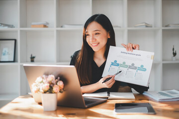 Business freelance concept, Smiling young Asian businesswoman explains sales trends with a chart...