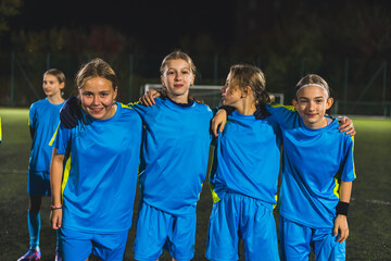 medium shot of a group of cute little girls wearing blue uniforms at the football practice at night. High quality photo