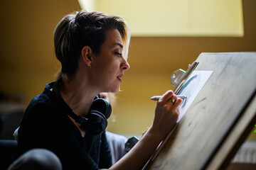 Side view of professional illustrator pencil drawing portrait at home.