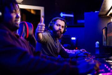 Bearded male gamer showing thumb up while playing online strategy video game