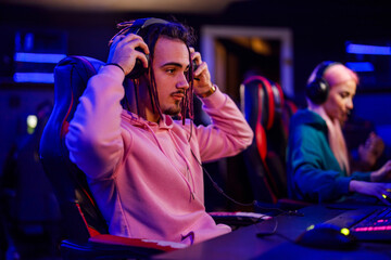 Young cybersport gamer with dreadlocks putting headphones on