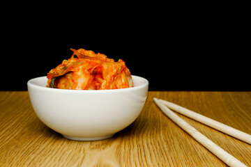 Kimchi in a white cup placed on a wooden table