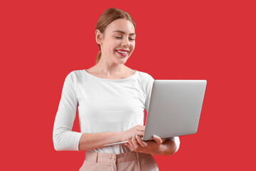 Female programmer working with laptop on red background