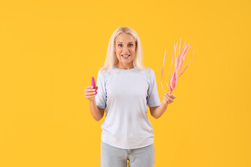 Mature woman with vibrator and whip from sex shop on yellow background