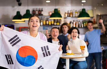 Group of happy friends with flag of South Korea celebrating victory of their favorite team in a...