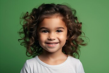 Portrait of a cute little girl with curly hair on a green background