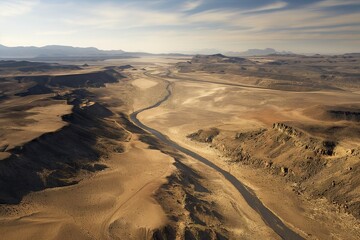 Fototapeta na wymiar A river snakes through a barren desert landscape in an aerial view.