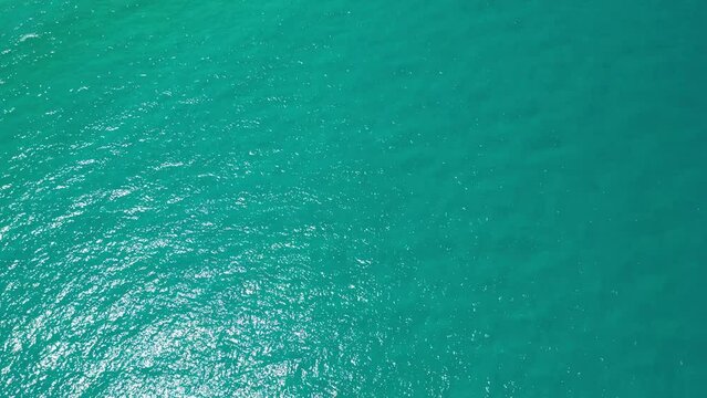 Top View Slow motion looping c ripples and wave, Refraction of sunlight top view texture sea side, Foaming and Splashing in the Ocean, Sunny Day, Slow Motion. Halkidiki, Greece. Veiw from drone