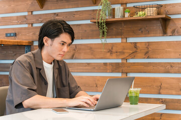 カフェ・家でノートパソコンを使う若い男性（テレワーク・リモートワーク）
