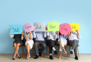 Business people holding speech bubbles with words near blue wall