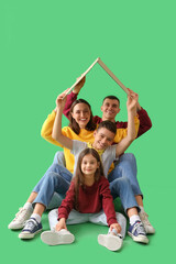 Little children with their parents and cardboard paper on green background