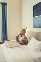 Hombre joven tatuado y fitness posando en ropa interior en habitación de hotel