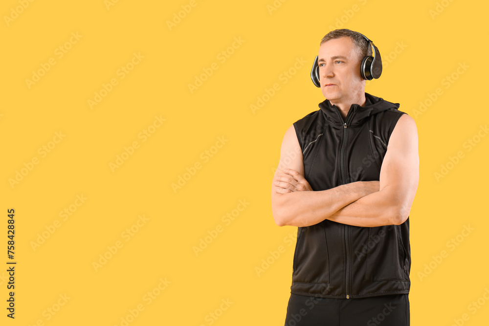 Sticker Portrait of sporty middle-aged man in headphones on yellow background