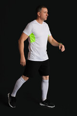 Fototapeta na wymiar Portrait of sporty middle-aged man walking on black background