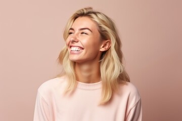 Portrait of a beautiful young blond woman smiling over pink background.