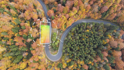 Electric car on curved autumn road with graphic of battery indicator. Aerial - obrazy, fototapety, plakaty