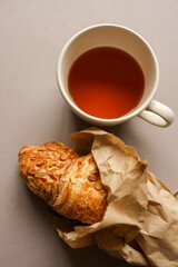 Cup of tea and delicious croissant top view, copy space