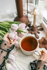 Cup of tea, bouquet of pink tulips and candles, spring aesthetics