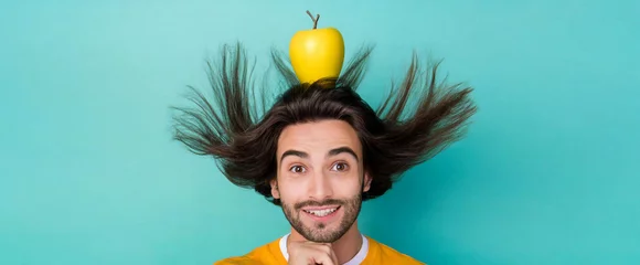 Fotobehang Funny young man with long hair in the air. Unconventional advertising portrait of a guy with apple above her head © juanorihuela