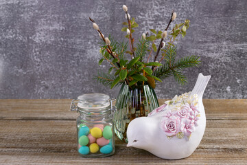 Easter colorful candies, pussywillow and a figurine of bird on the table.