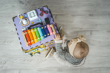 Busy Board. A child plays with pleasure with a toy model at home, which is intended for the...