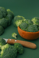 Broccoli in a wooden bowl on a green background