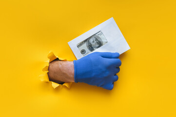The right male hand in a blue fabric work glove holds an envelope with dollar bills (money). Torn...