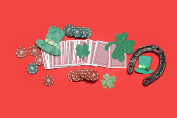 Poker chips, cards, leprechaun hat and lucky clovers on red background. St. Patrick's Day...