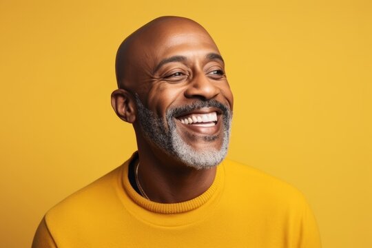 Portrait of a happy senior African American man laughing against yellow background