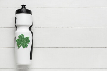 Sport bottle with clover on white wooden background. St. Patrick's Day celebration