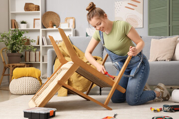 Beautiful young happy woman assembling furniture at home