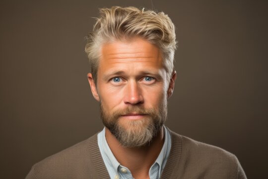 Portrait of a handsome man with blond hair and beard on a brown background