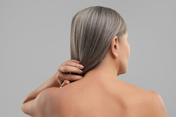 Mature woman with healthy skin on grey background