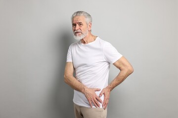 Arthritis symptoms. Man suffering from hip joint pain on gray background