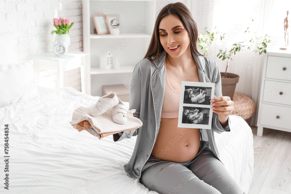 Sticker Young pregnant woman with baby clothes and sonogram image sitting in bedroom